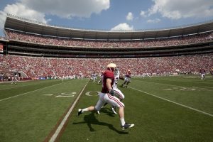 NCAA Football Player running with support of Booster Club Stadium funding