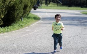 Little kid running with booster club printed T-Shirt on